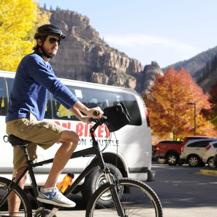 Image of a man sitting on his hybrid bike as he stages in front of the Canyon Bike Shuttle to begin his ride in the Glenwood Canyon